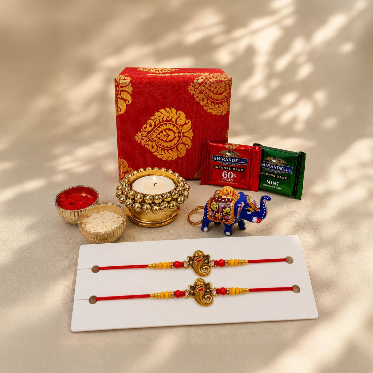 Red and gold brocade rakhi with ornate golden elephant pendants included in raksha bandhan gift hamper for brother and bhabhi