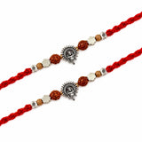 Silver sunburst charm rakhi with intricate ganesha design, brown wooden beads, and silver floral accents for raksha bandhan