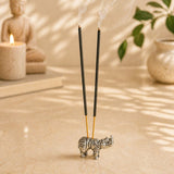 Minimalist german silver rhinoceros incense stick holder with textured surface and two black incense sticks emitting smoke
