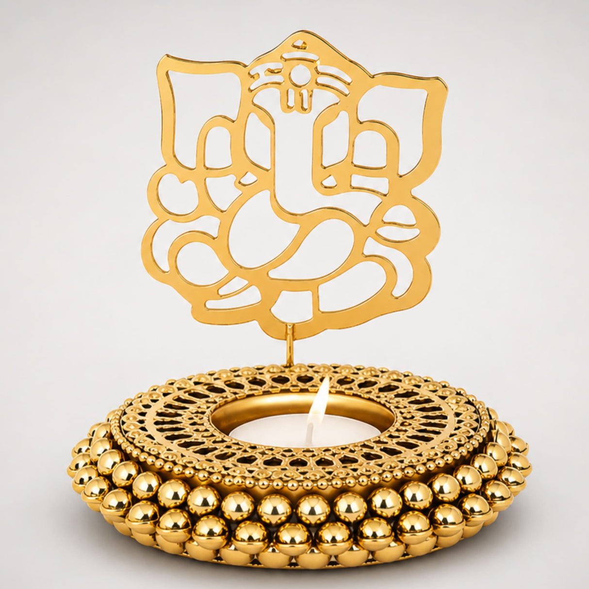 Golden ganesha-themed tealight candle holder with intricate cut-out design and beaded base for festive home decor