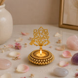Golden ornate tealight candle holder with intricate filigree, beaded base, and seated deity motif for festive decor