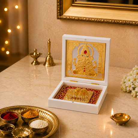 White box containing a gold plated ganesh photo frame with red accents on an ornate tray for home temple decor