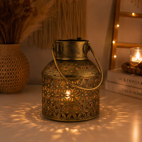 Antique brass lantern tealight candle stand with intricate floral cutouts and sturdy handle glowing warmly inside
