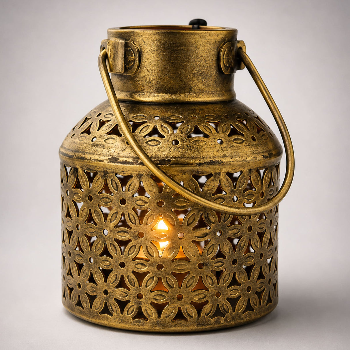 A brass gold iron tealight candle stand with intricate floral cutouts glowing warmly for home office decor and diwali gift