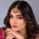 Gold-plated chand tikka with red and green gemstones featuring an ornate floral design for indian traditional weddings