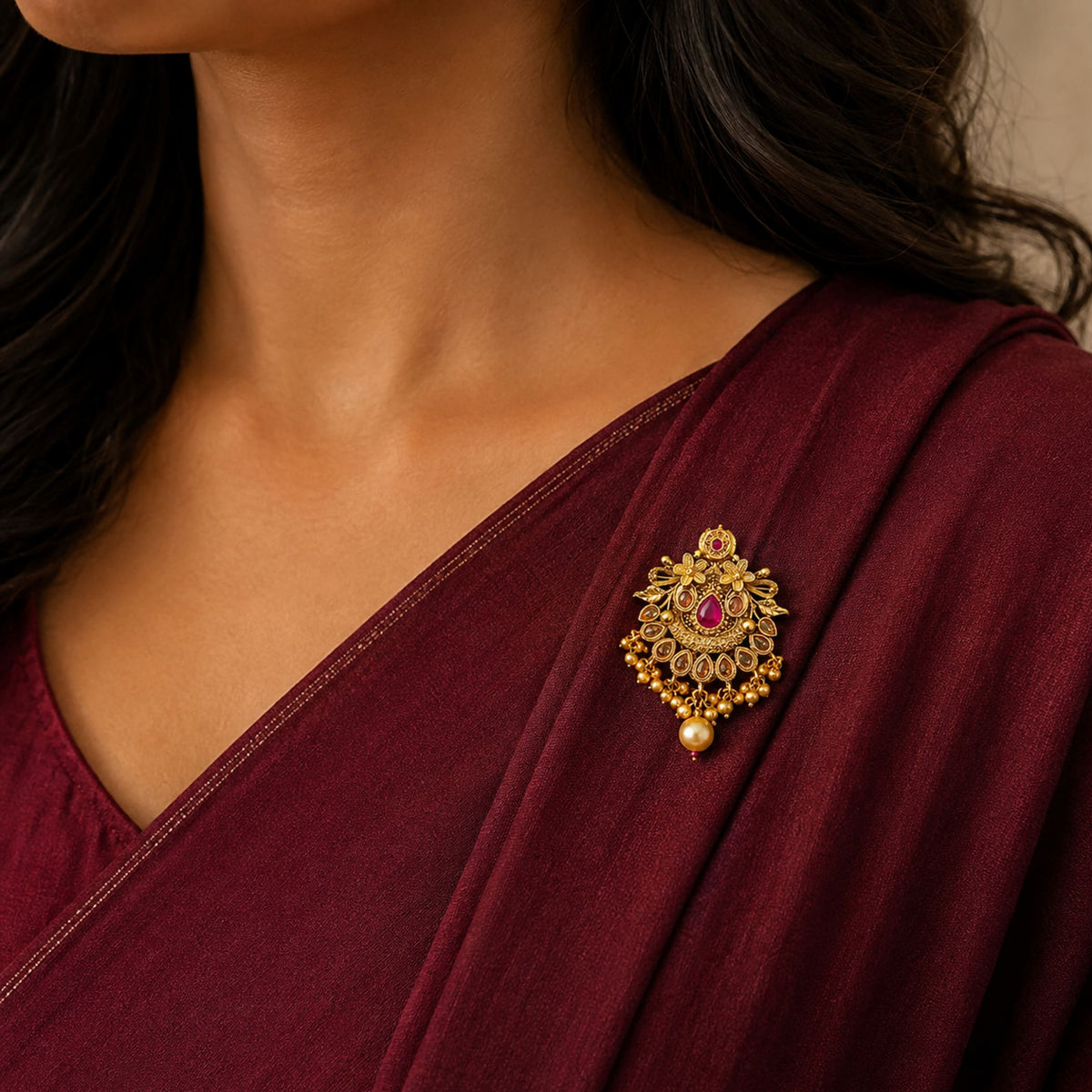 Gold-colored ornate sari brooch with red gemstone, pearl, and beads for Indian saree wedding accessories