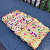 A vibrant yellow silk unstitched blouse piece with colorful floral and paisley motifs for Indian return gifts