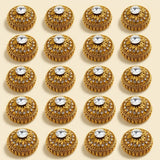 Golden metallic kumkum holder with ornate golden buttons featuring embossed patterns and clear rhinestones for pooja