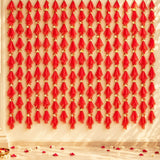 Red sheer fabric fan decorations with gold accents hanging in vertical rows for gotta patti net backdrop decor