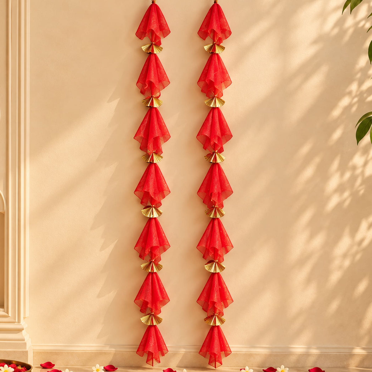 Red sheer fabric tassels with gold metallic fan accents hanging in vertical strands on gotta patti net backdrop for diwali and weddings