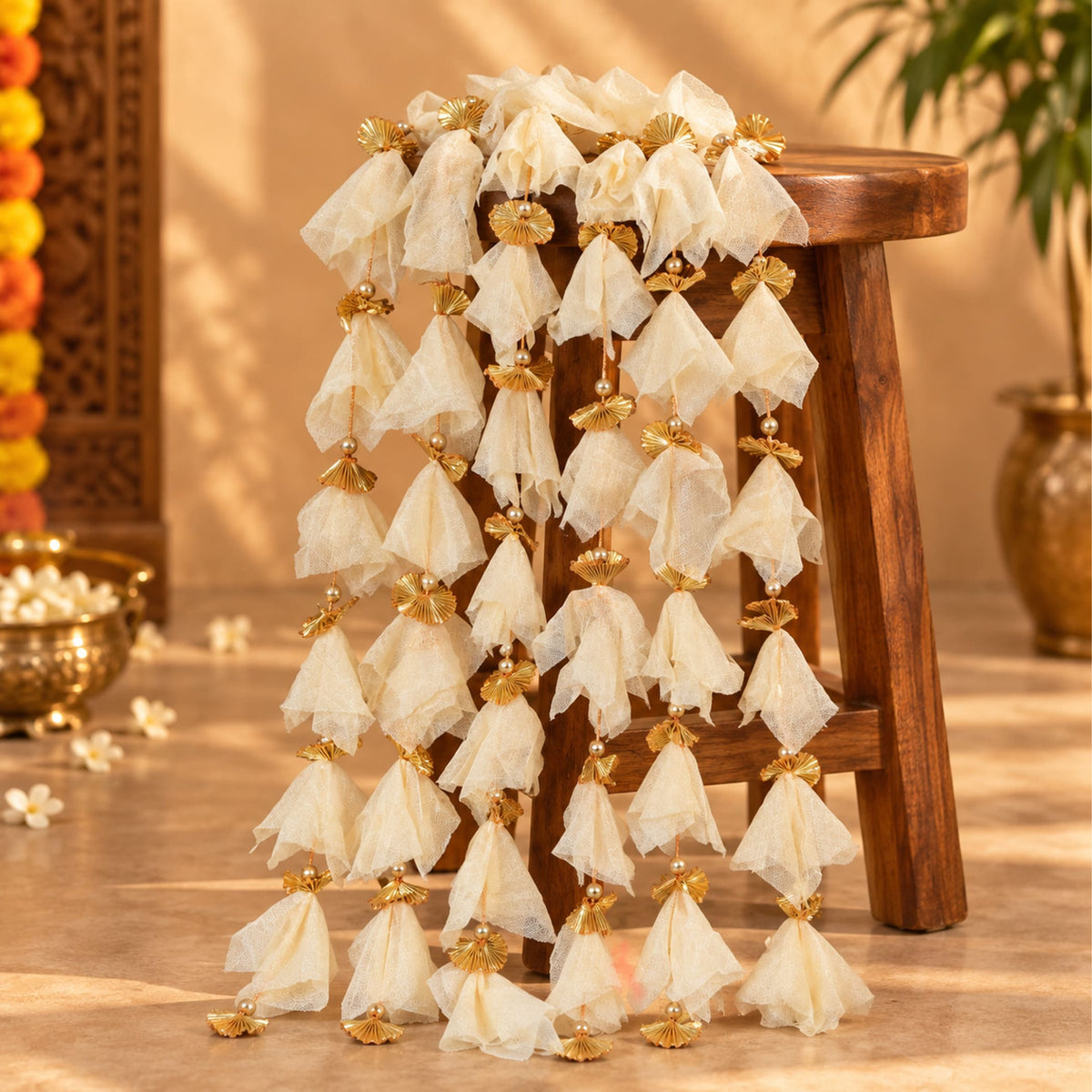 A delicate ivory tulle gotta patti net backdrop garland with golden fan embellishments and pearls for diwali eid wedding decor