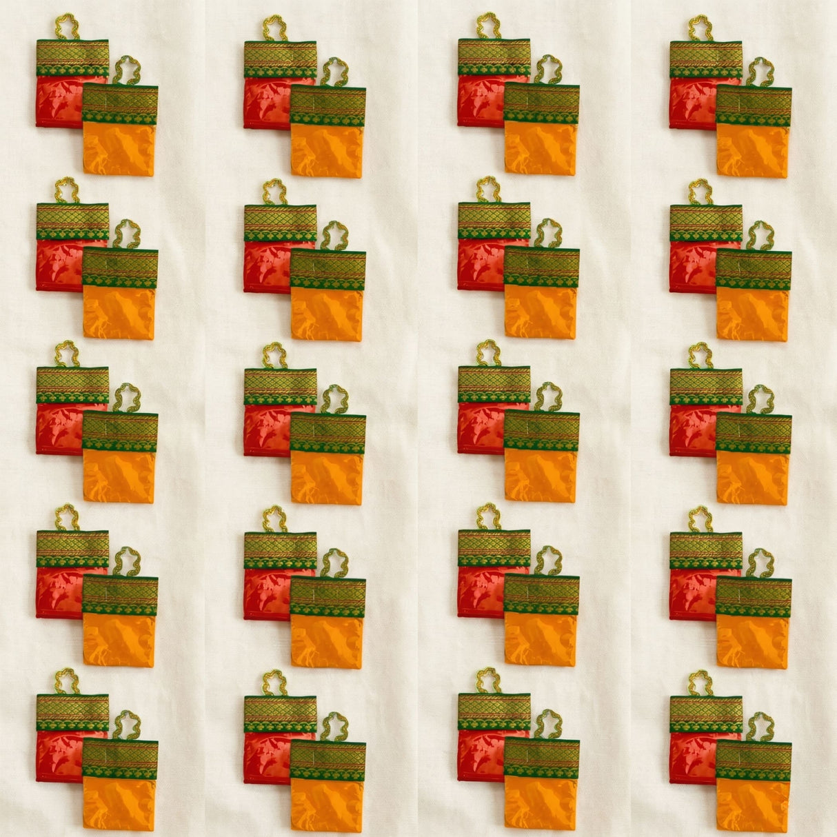Red and orange satin haldi kumkum packets with green embroidered borders and gold metal loops for hindu wedding puja