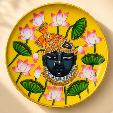 Vibrant yellow hand painted wooden decorative plate with dark skinned deity and lotus flowers for wall decor