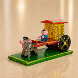 Hand-painted Indian wooden bullock cart decor with pink-faced driver in blue attire and red yellow accents for home display