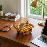 A vibrant orange hand-painted wooden trolley with wheels holding a cup of tea and sugar bowl for serving snacks