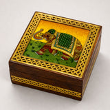 A small wooden jewelry box with golden lattice border and handcarved green gold brown elephant design on lid