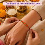 A vibrant orange and gold handmade designer rakhi bracelet with intricate metallic designs worn for raksha bandhan