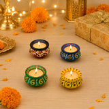Four hand-painted matki clay diya lamps with vibrant colors and lit candles for diwali pooja decoration