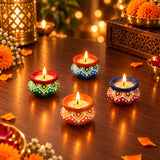 Four colorful handmade clay matki diyas filled with wax and lit candles for Diwali pooja and home decor