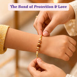 Designer gold-colored rakhi threads with red and white beads and ornate central design for brother and bhabhi gift