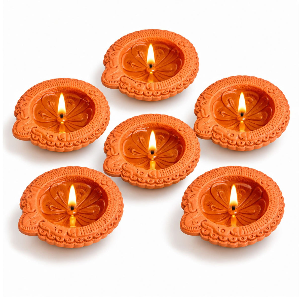 Set of six handmade terracotta clay diyas with intricate floral embossing and lit candles for diwali and pooja decoration