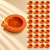 Handmade orange terracotta clay diya with intricate floral embossing and lit wick for pooja and Diwali decoration