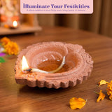 Terracotta-colored handmade clay diya with intricate embossed patterns and a lit wick for pooja and diwali decor