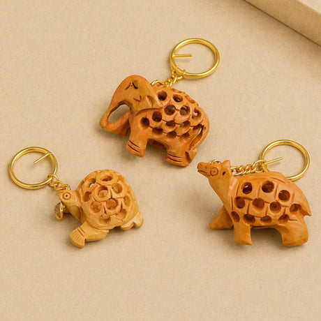 Three handmade wooden keychains with intricate elephant and turtle patterns on gold-toned metal rings for good luck charms