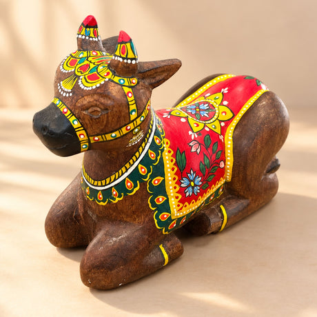 Hand-painted wooden nandi cow idol with vibrant red yellow and green floral patterns for home temple pooja decor
