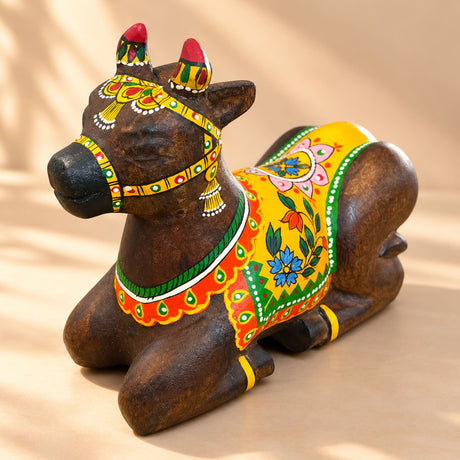 Hand-painted wooden nandi cow idol with vibrant yellow red and green floral patterns for home temple pooja decor