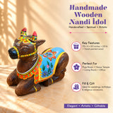 Handmade wooden Nandi cow idol with hand-painted blue orange floral cloth gold trimmings and red-tipped horns for pooja decor