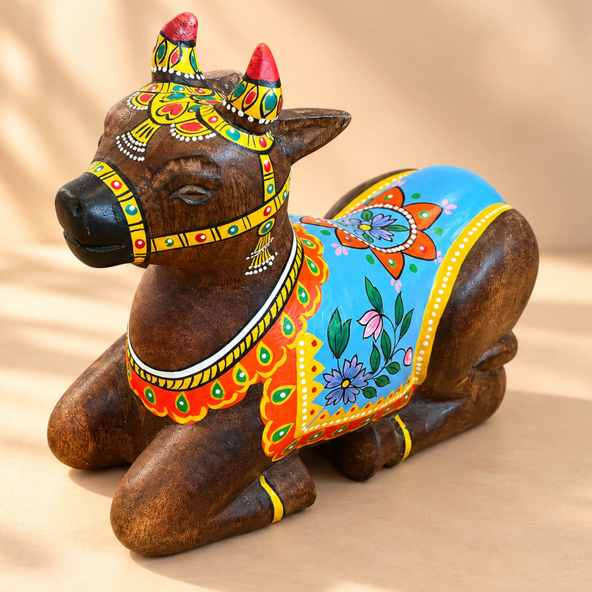Hand-painted wooden Nandi cow idol with vibrant blue orange and yellow floral patterns for home temple decor
