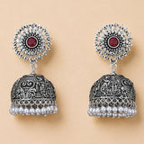 Boho oxidized silver tone jhumka earrings with intricate filigree, central red gemstone, clear stones, and pearl dangles for ethnic wear
