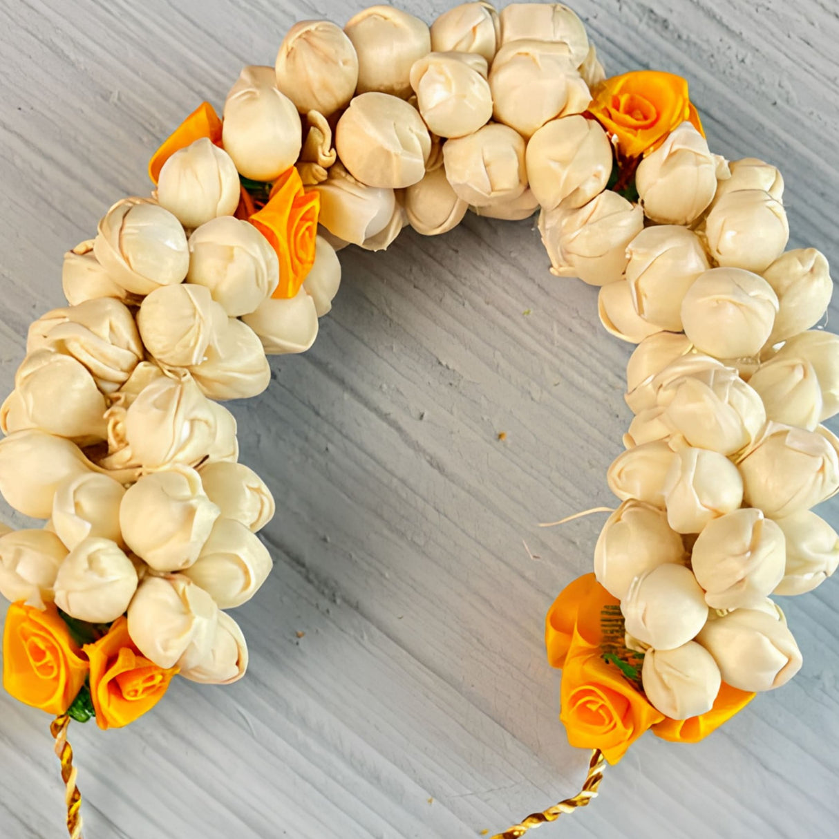 A decorative traditional artificial jasmine gajra for hair with cream and orange artificial roses for bridal weddings