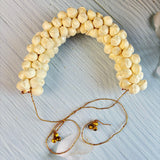 A delicate cream-colored traditional artificial jasmine gajra with fabric petals gold chains and bells for bridal hair accessory