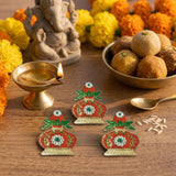 Three ornate red and gold decorative diya-shaped kalash haldi kumkum holders with green leaf accents and jeweled centers
