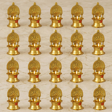 Golden brass Kamakshi Deepam oil lamps with intricate deity carvings and small lit candles for Diwali pooja