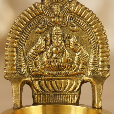 Golden brass diya featuring intricately detailed lakshmi statue seated on lotus for Hindu puja and home decor