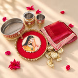 Red velvet karwa chauth pooja thali set with gold beaded border and central portrait of ornate indian woman in yellow attire