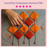 Orange and red diamond-shaped haldi kumkum packets with gold bead detailing and tassels for hindu wedding and puja