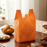 Bright orange reusable non woven tote bag with black geometric indian kolam print for weddings and puja events