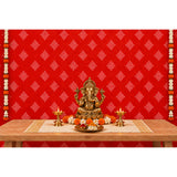 Golden ganesha statue with intricate detailing seated on pedestal with marigold and white flowers in kolam rangoli backdrop set