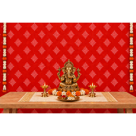 Golden ganesha statue with intricate detailing seated on pedestal with marigold and white flowers in kolam rangoli backdrop set