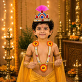 A child in vibrant yellow traditional attire wearing a gold and gemstone jewelry set with a jeweled crown and pink feathers