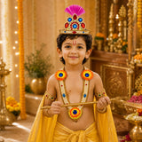 A young boy wearing a vibrant yellow dhoti and a golden crown with pink feathers in a janmashtami jewelry set