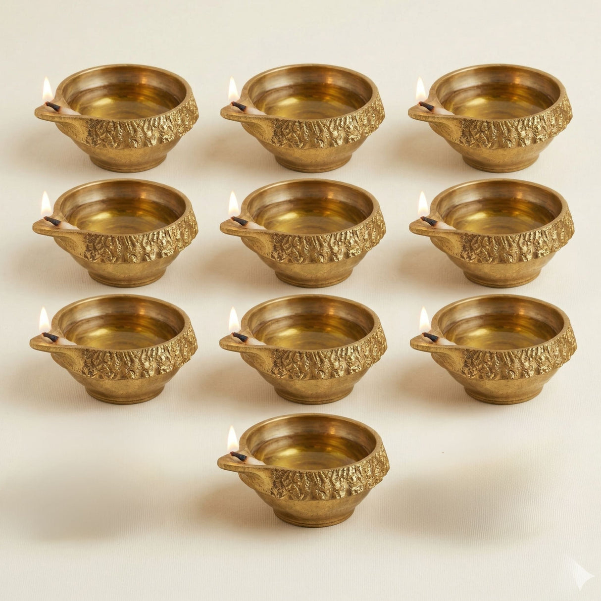 Golden brass kuber diya oil lamps with intricate embossed patterns and side handles for diwali puja decoration