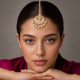 A delicate gold-toned kundan chand tikka with pink enamel white pearls and clear stones for Indian wedding wear