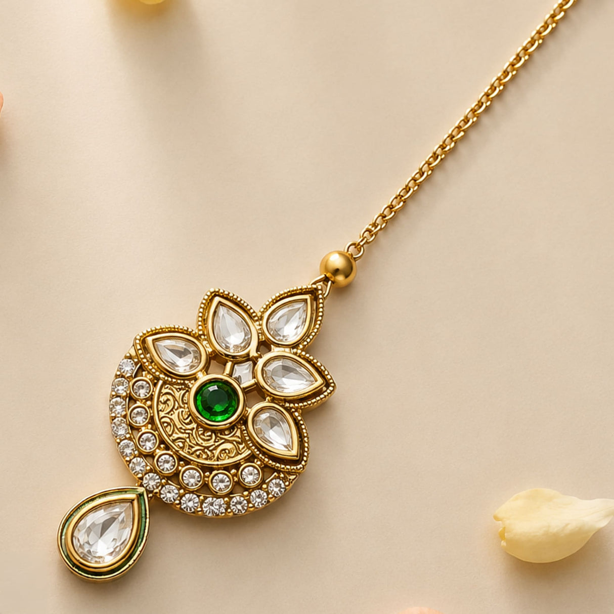 Gold-plated kundan work maang tikka with central green emerald teardrop and round stones for traditional indian weddings