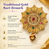 A traditional gold sari brooch with intricate sunburst design and green pink gemstones for bridal wedding accessories