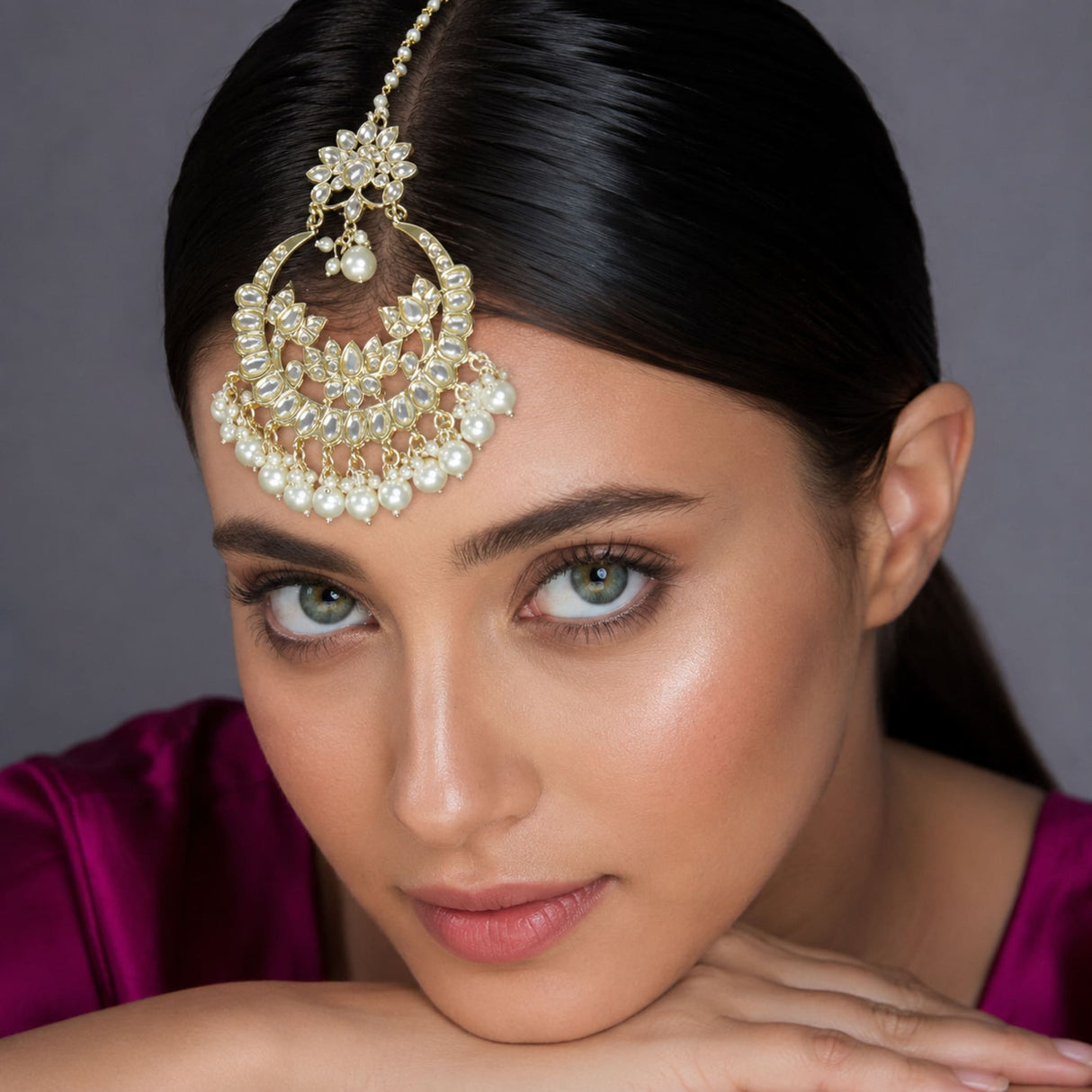 A gold-plated kundan maang tikka with sparkling crystals and pearls featuring an intricate floral design for weddings